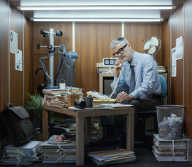 Office worker having a phone call in his tiny room