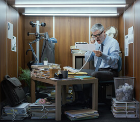 Office worker having a phone call in his tiny room