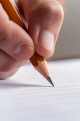 Fingers holding pencil writing on paper. Creativity and education in action concept.