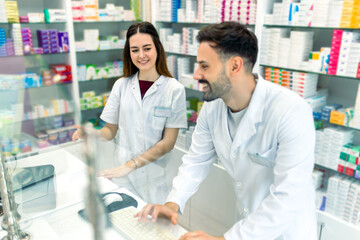 Obraz premium Two young woman pharmacist using computer at counter.