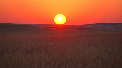 Fototapeta premium Fiery sunset over fields with a lone wind turbine