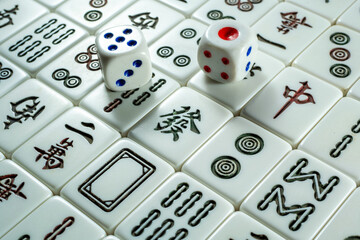 A close-up of Mahjong tiles with two dice placed on top, featuring symbols and characters in a traditional game setup.