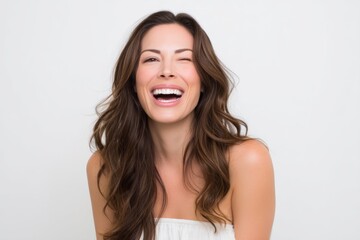 Beautiful woman winks and laughs against a white backdrop for beauty advertising