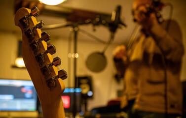 A man plays the violin in a recording studio, using a professional condenser microphone.