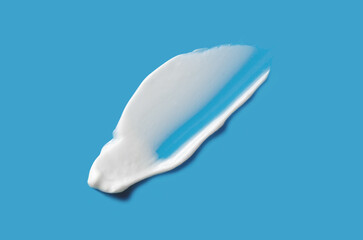 A sample of white cosmetic moisturizer on a blue background