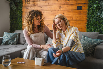 daughter takes care of sick mother with high blood pressure