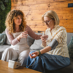 daughter takes care of sick mother with high blood pressure