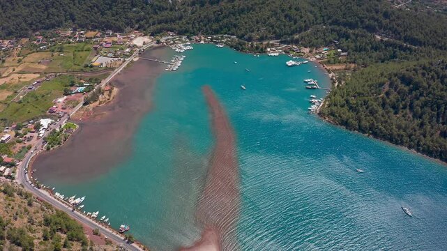 Bird's eye view of the unique Kızkumu Beach and its surroundings in Marmaris, Muğla, taken with a drone. The path formed by the red sands in the sea, turquoise waters and lush green nature