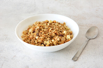 a bowl of muesli with a spoon on gray background