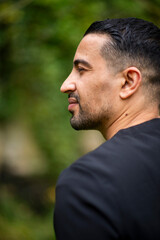 Obraz premium Profile of young hispanic male in outdoor setting with natural background