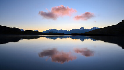 Fototapeta premium Serene mountain lake at sunrise, pink clouds reflecting on calm waters, surrounded by tranquil nature and peaceful morning light.
