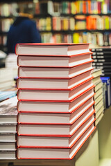 Stack of red hardcover books neatly arranged on bookstore display. Books represent knowledge, reading, literature and modern publishing