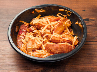 Ready made dish with wedges, garlic sauce and cheese in plastic tray on wooden table surface. Fast food made of high quality products ingredients. Lunch for cooking in microwave.