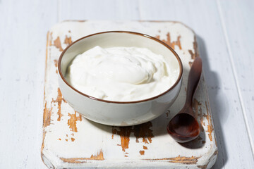 greek yogurt in a white bowl on a wooden board