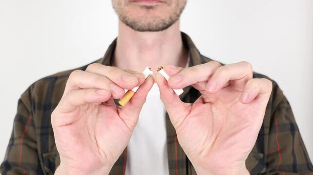 Close-up of a man, breaking a cigarette in front of himself with his hands, the concept of quitting smoking, quitting smoking, World No Tobacco Day on May 31. avoiding quitting smoking