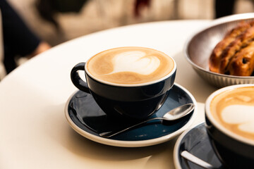 Café cappuccino en gros plan dans une tasse avec un latte art coeur servi sur une table de terrasse de café