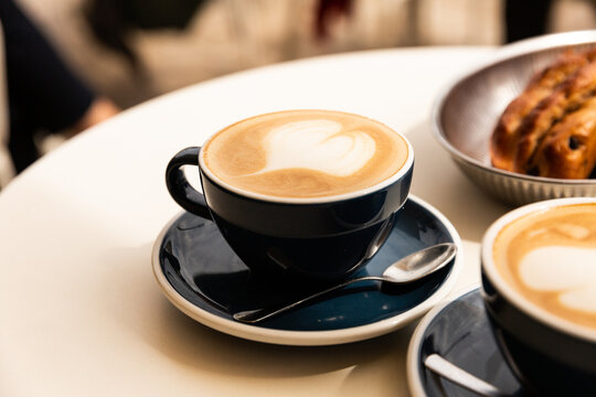 Café cappuccino en gros plan dans une tasse avec un latte art coeur servi sur une table de terrasse de café