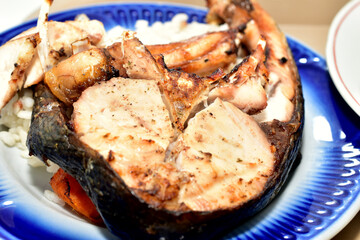 A fried fish steak lies on a plate with vegetables.