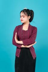 A young woman with a displeased expression crosses her arms and looks away in frustration, wearing...