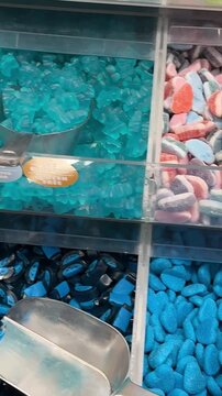 Candy shop display with colorful sweets in transparent bins, including gummy bears and jelly beans