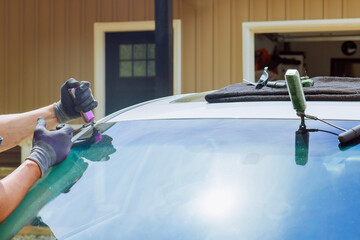 Technician skillfully worker replaces car windshield outside an auto service center.