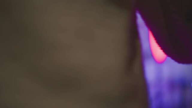 Close up metallic door handle turning open on dark frame revealing vibrant neon lit game room with pink purple and blue hues as person silhouette steps inside through ajar door under moody glow