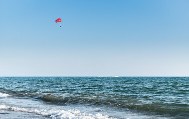 A red parachute flies over the sea