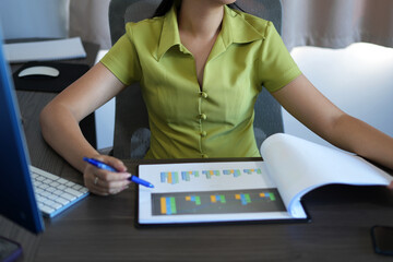 Young asian woman is stressed depressed while working on laptop and paper works on graphs, and suffering from headache at office, feeling sick at work and she has to finish the data analysis in time.