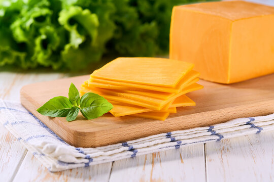 cheddar cheese slices on a light kitchen table, selective focus.