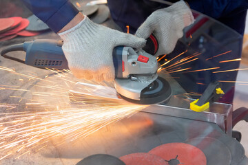Mechanic using angle grinder and working with metal in workshop