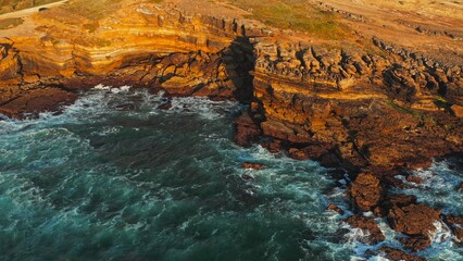 Ocean waves rolling to the rocky shore. Beautiful seascape. Aerial top view of the beautiful ocean rocky shore with rolling waves. 