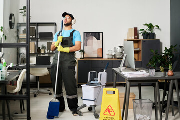 Cleaning worker imitating singer during work in office room
