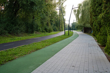 Serene pathways intertwine through tranquil greenery at dusk in an urban park filled with calm reflections and gentle breezes