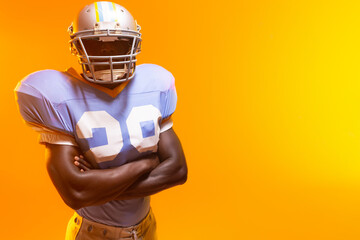African American male football player crossing arms in studio, wearing helmet and pads, copy space © WavebreakMediaMicro