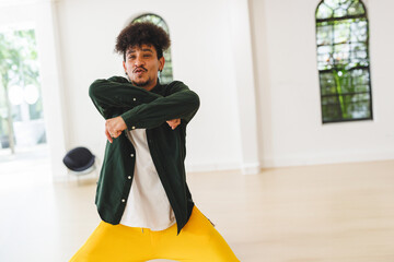 Man dancing in modern dance studio with glass doors, arched window and black seat