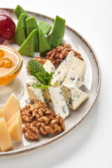 Plate presenting delicious cheese selection with honey and walnuts