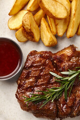 Grilled steak with potato wedges and red wine sauce, overhead view