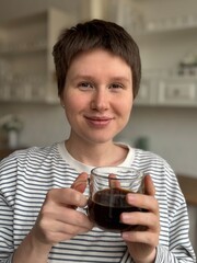 young modern woman drinking black americano coffee in the morning in the kitchen, enjoying the moment