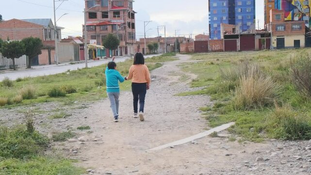 latin children brothers back to back walking holding hands in the streets of the city of el alto in bolivia , latin america - concept of friendship