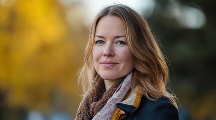 A confident woman smiling in nature with autumn colors around her. The joy in her expression reflects warmth and positivity.