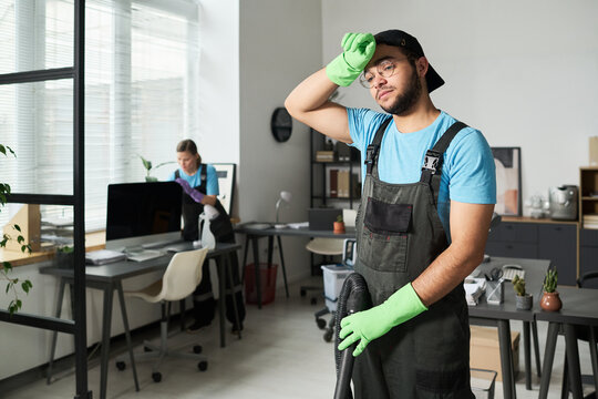 Cleaner in uniform tired after cleaning in office room