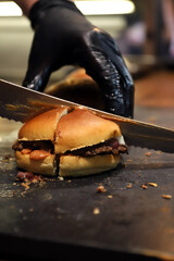 che cortando hamburguesa con su cuchillo y manos con guantes