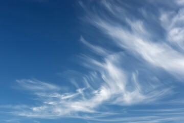 Obraz premium White cirrus clouds moving across a serene blue sky, creating a mesmerizing display of nature's artistry