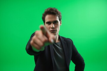 Young businessman pointing his finger towards the camera on a green screen background, ideal for chroma keying and compositing
