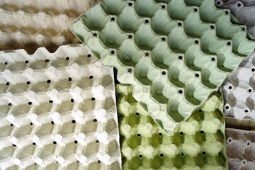 Caring for the environment: collecting egg carton for recycling. Photographed from above, grey and green containers with compartments for storing and transporting chicken eggs are carelessly laid out