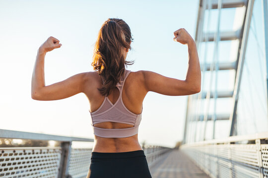 Fit Woman Flexing Muscles Outdoors on Bridge During Fitness Workout