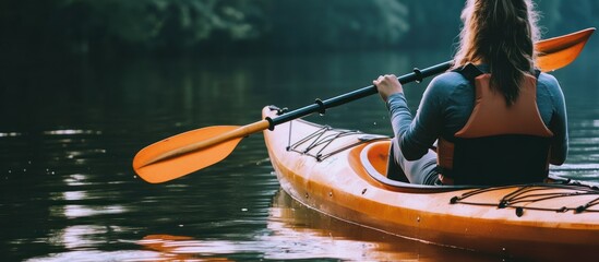 Obraz premium Woman kayaking on a peaceful lake, enjoying outdoor activities in nature