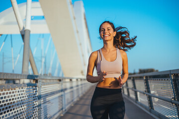 Smiling Woman Jogging Outdoors on a Bridge During a Bright Sunny Day