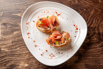 Two elegant bruschettas topped with smoked salmon, cream cheese, and microgreens, elegantly plated...