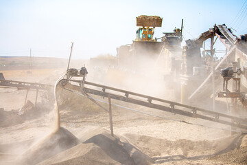 Vibrating screen stone crusher in operation. Crushing stones in a quarry for processing minerals, cement, limestone. Heavy and mobile equipment in a quarry for processing stone into building material.